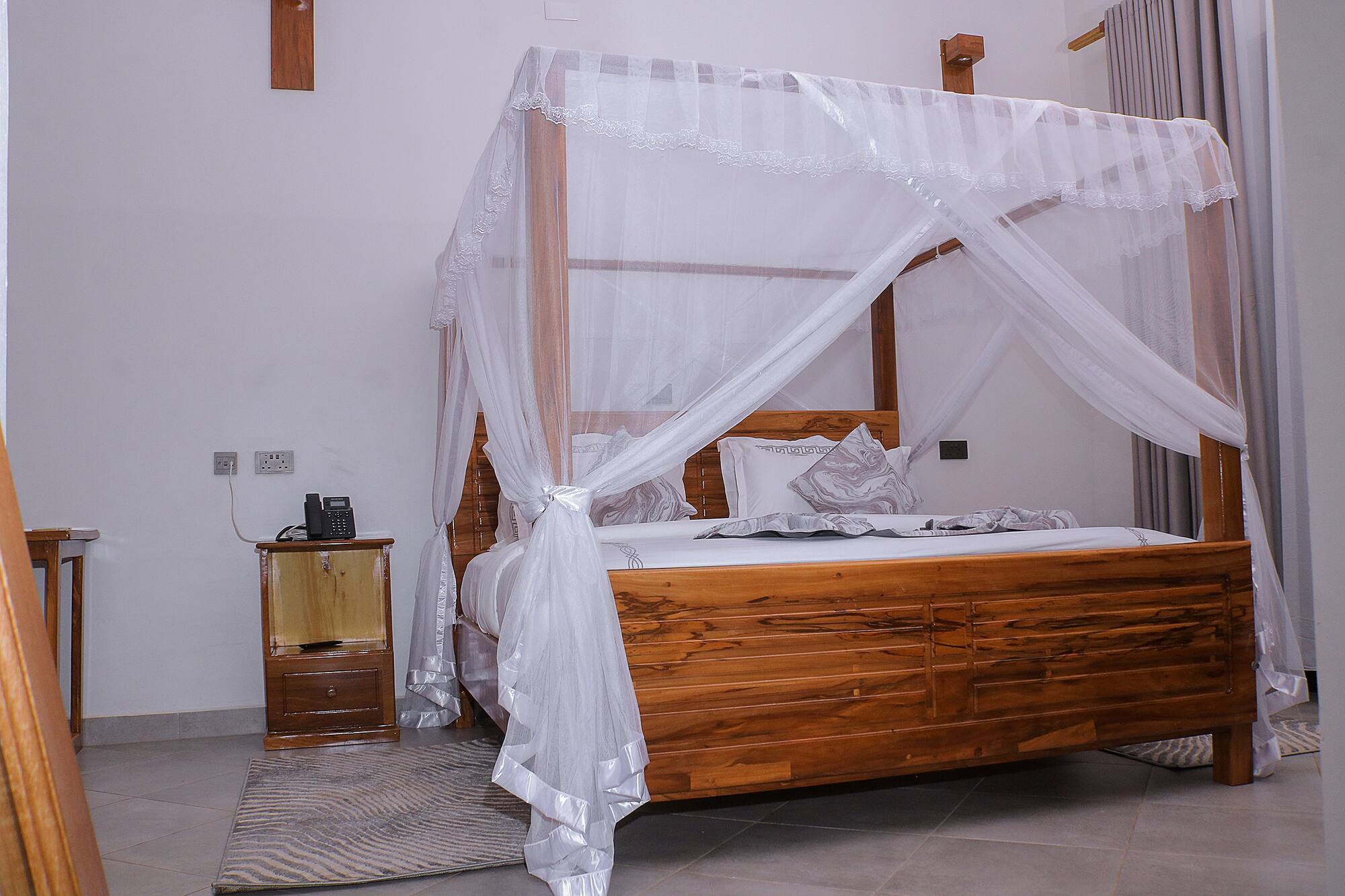 A Hati Residences garden room with a carved four-poster bed in daylight